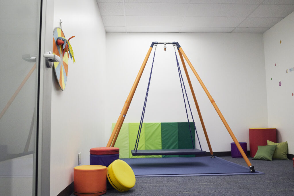 A Colourful indoor swing set with sensory toys and seat options for children.