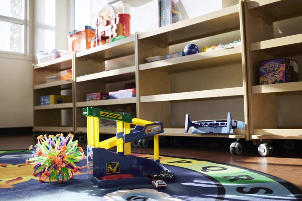 Colouful children's toys on a carpet on the floor, and in organizers along a wall.